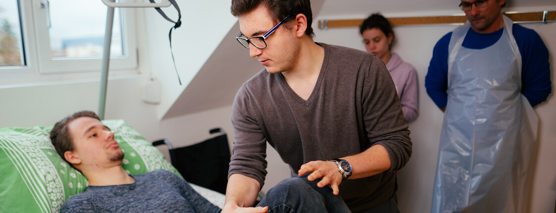 Schüler übt im praktischen Unterricht von Pflegetechniken an einem Mitschüler.