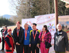 Athlet*innen mit Medaillen stehen vor Bannern des Wintersporttags im Freien
