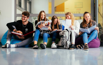 Ein Schüler und fünf Schüler*innen sitzen auf Sitzsäcken im Gand der Schule und lernen miteinander.